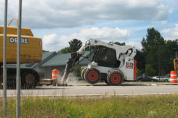 Kadlec Excavating Bobcat skidloader breaking highway concrete.